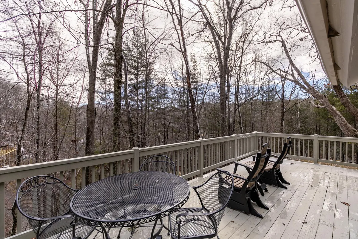 A serene outdoor deck setup with comfortable seating and a wooded view beyond the deck railing. The scene invites relaxation, reading, or quiet moments with your furry friend after a day of adventure.