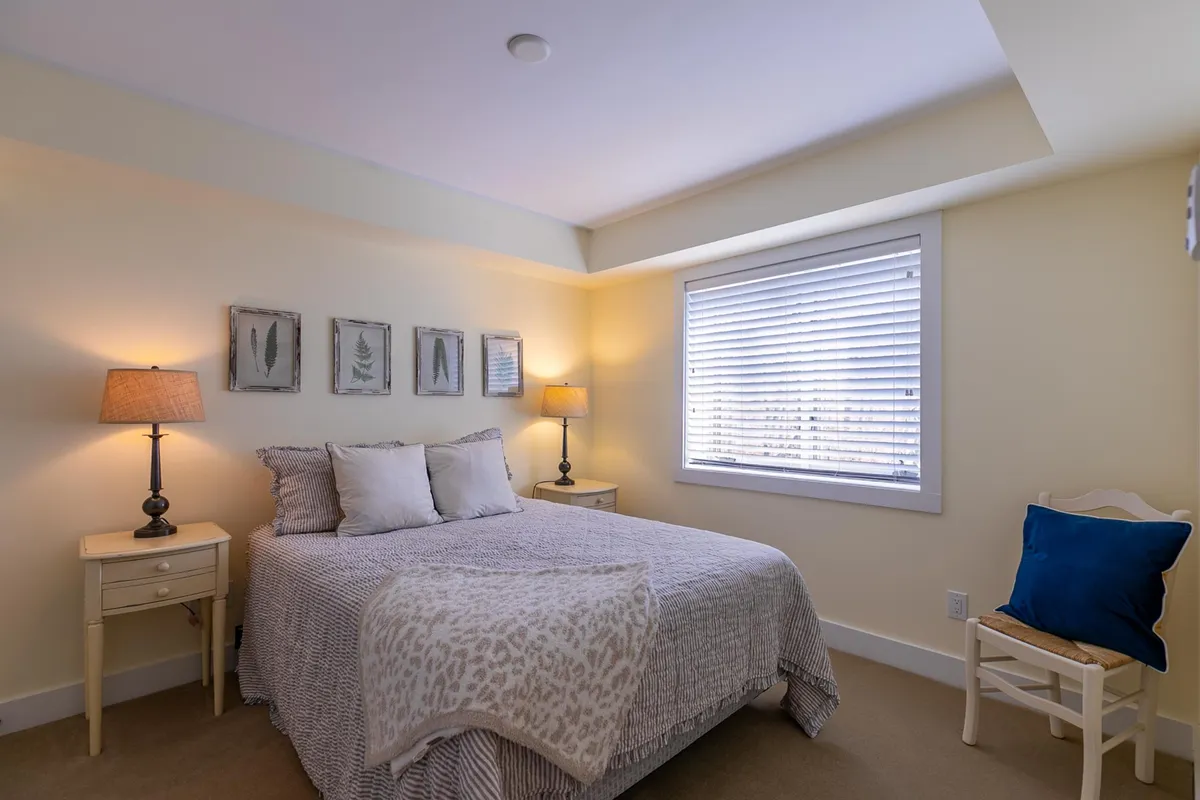 A cozy bedroom featuring a Queen bed adorned with a patterned throw, soft lighting from table lamps, and framed artwork on the wall. The atmosphere is tranquil and intimate, ideal for relaxation after a long day outdoors.